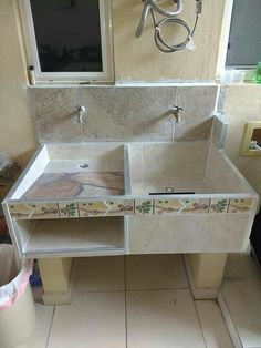 a bathroom sink sitting under a window next to a tiled floor and counter with two faucets on it