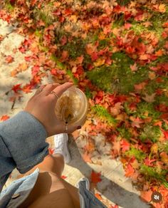 a person sitting on the ground with their feet up and holding a cup in front of them