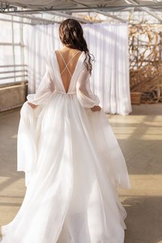 the back of a woman in a white wedding dress with long sleeves and open shoulders