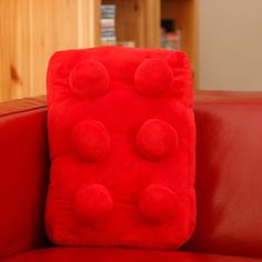 a red couch with pom - poms on it in front of a bookshelf