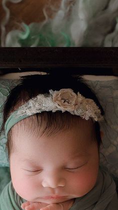 a baby is sleeping with her eyes closed and hands clasped to her chest, wearing a headband