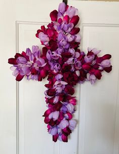 a cross made out of purple flowers hangs on a door