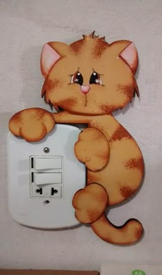 an orange cat sitting on top of a white light switch cover with its paw up