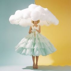 a woman in a white dress is holding a cloud over her head