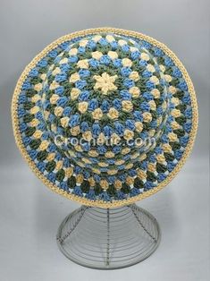 a crocheted blue and yellow dishcloth on a metal stand with a white base