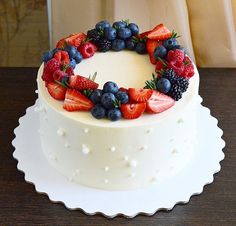 a white cake topped with berries and blueberries