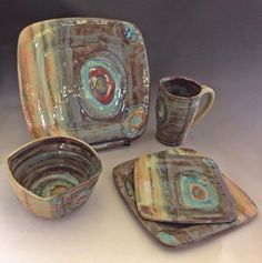 an assortment of ceramic dishes and cups on a table