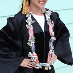 a woman wearing a graduation gown and holding a cell phone in her hand while standing next to a blue wall