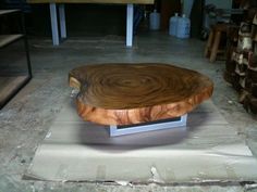 a wooden table sitting on top of a white tile floor next to stacks of wood