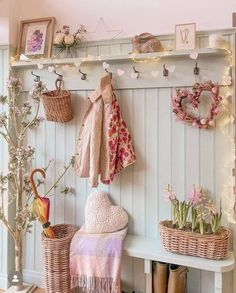 a white bench topped with baskets filled with flowers and umbrellas next to a wall mounted coat rack