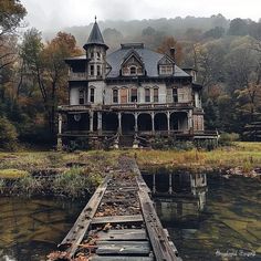 an old house sitting on the edge of a body of water in front of a forest