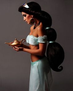 a woman dressed as disney princess holding a teapot and looking down at her stomach