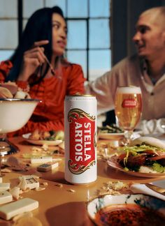 two people sitting at a table with food and drinks