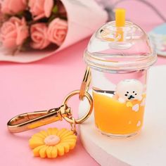 a glass jar with a keychain and some flowers on the table next to it