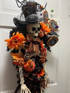 a skeleton wearing a hat and holding a pumpkin in front of a door decorated for halloween