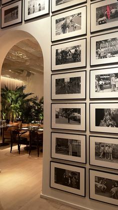 a wall full of black and white photos in a restaurant with arches leading into the dining room