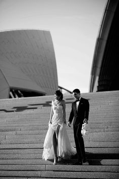 black and white photo of bride and groom walking up stairs in front of the sydney opera house