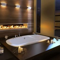 a bathtub with candles on the side and lights in the wall above it that illuminates fire