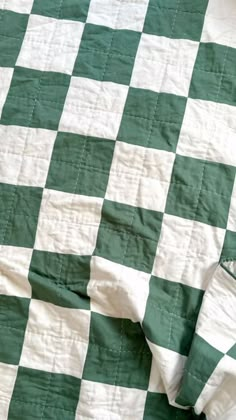 a green and white checkered blanket laying on top of a bed