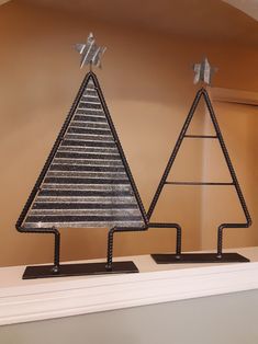 two metal christmas trees sitting on top of a mantle