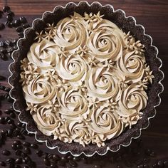 a pie with chocolate frosting on top and coffee beans around the edges next to it