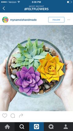 a person holding a glass bowl filled with fake flowers