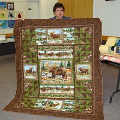 a woman holding up a quilt with pictures of animals on it in the middle of a room