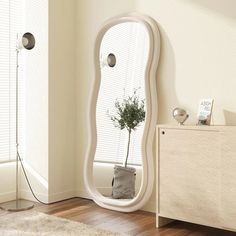 a large white mirror sitting on top of a wooden dresser next to a plant in a pot