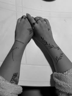 two hands holding each other with tattoos on them