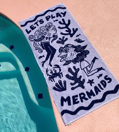 a towel that is next to a swimming pool with the words let's play mermaids on it