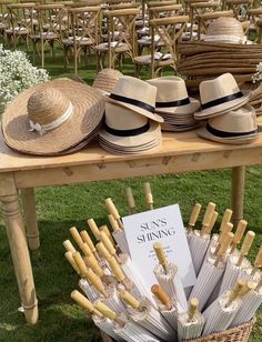 straw hats and wine glasses on a table at an outdoor wedding ceremony with chairs in the background