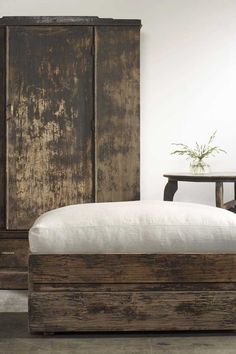 a bed sitting next to a wooden cabinet and table