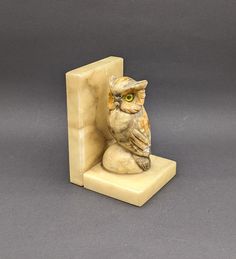 an owl figurine sitting on top of a stone block in the shape of a door