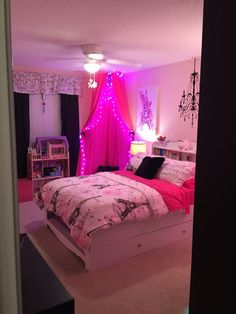 a bedroom decorated in pink and black with fairy lights on the ceiling, bedding and curtains