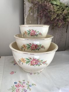 three bowls are stacked on top of each other in front of a flowered wall