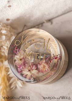 a jar with some flowers in it sitting on a white surface next to dried grass