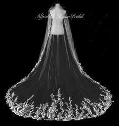 a black and white photo of a wedding dress with flowers on the bottom, veiled in