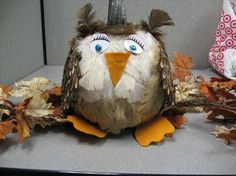 a stuffed owl sitting on top of a pile of leaves