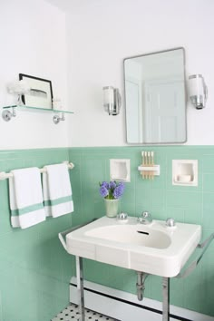 a white sink sitting under a bathroom mirror next to a green tiled wall and floor