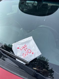 a piece of paper taped to the windshield of a car that says love is god