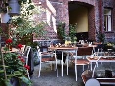 an outdoor dining area with tables, chairs and potted plants on the side walk