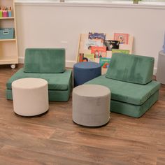 three different colored chairs and two stools in a room with wooden floors, bookshelves and children's toys