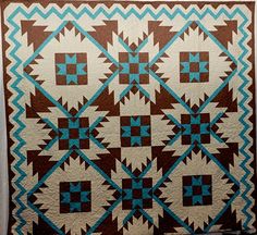 a brown and blue quilt hanging on a wall