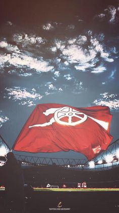 a large red flag flying in the air over a soccer field with people on it