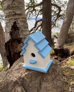 a blue and white birdhouse sitting on top of a rock