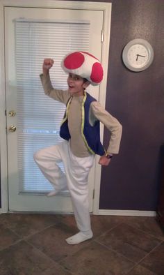 a young boy wearing a mushroom costume standing in front of a door with his arms up