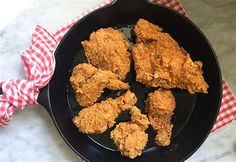 fried chicken in a frying pan with red and white checkered napkin on the side