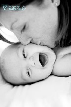 a man kisses his baby's forehead while laying on the bed in black and white