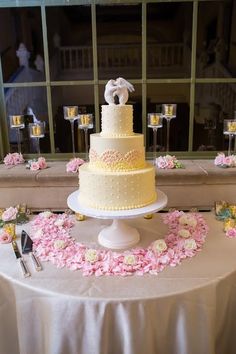 a wedding cake sitting on top of a table next to wine glasses and pink flowers