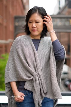 a woman wearing a gray shawl and blue jeans